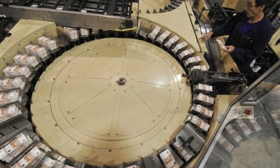 978776 25.10.2011 Машинист линии нарезки и упаковки укладывает пачки продукции в барабан для резки на фабрике ФГУП "Гознак" в Перми. Алексей Куденко/РИА Новости